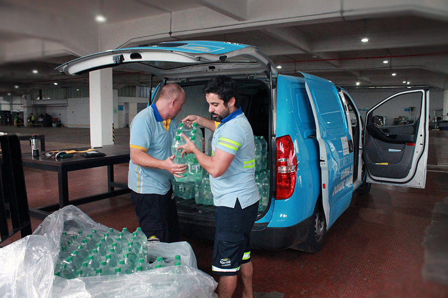 Funcionarios de Correo Uruguayo cargan fundas de agua embotellada en una camioneta