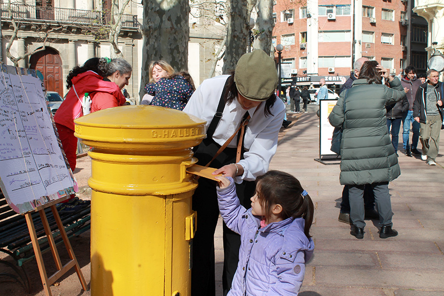 Niña coloca un sobre en el antiguo buzón