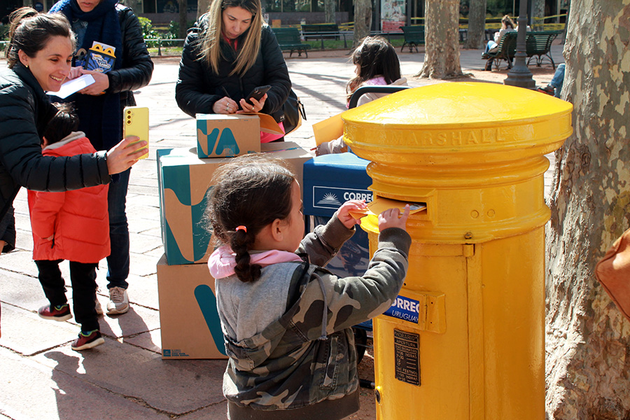 Niña coloca un sobre en el antiguo buzón